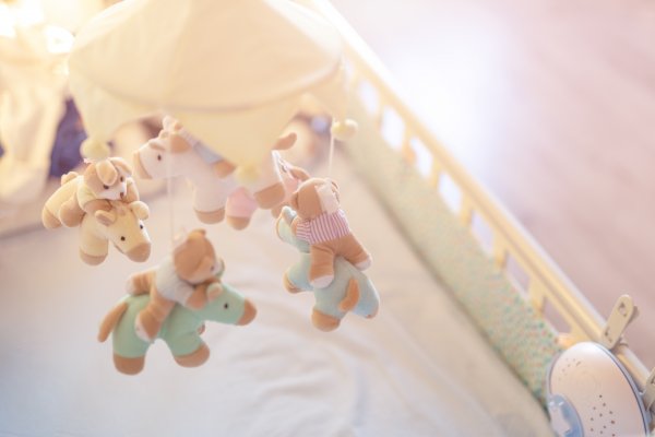 Overhead side shot of baby crib with toys above the mattress